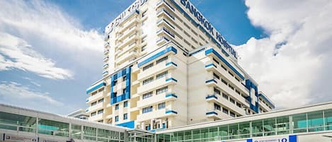 A multi-story hotel with a prominent 'Bangkok Hotel' sign, a modern glass entrance, and a clear sky.