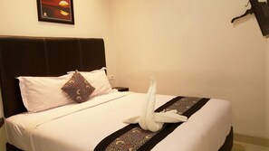 A neatly made bed with a white duvet, a patterned pillow, and a towel arranged on the bed.