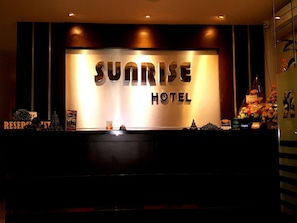 A reception desk with the sign "Sunrise Hotel" above it.