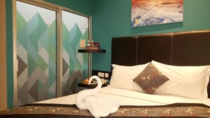 Een hotelkamer met een bed, een nachtkastje, een wandplank, een raam met geometrische gordijnen en een landschapsschilderij.