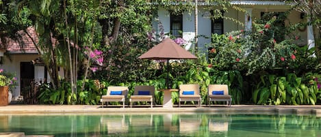 Una piscina al aire libre, sillones reclinables de piscina