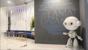 A modern interior with a robot figure, a glass partition, and a wall with multilingual text. - PassGo Digital Airport Hotel Terminal 3 Soekarno Hatta (Tangerang)