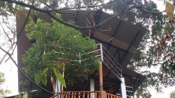 A multi-level wooden structure with a stone base, surrounded by trees. - Ella camping Resort (Ella)