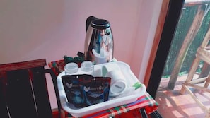 Una mesa con una cafetera, tazas y bolsitas de té.