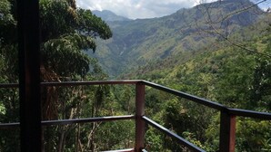 A view from a balcony with a metal railing, overlooking a lush valley with dense greenery and distant mountains. - Ella camping Resort (Ella)