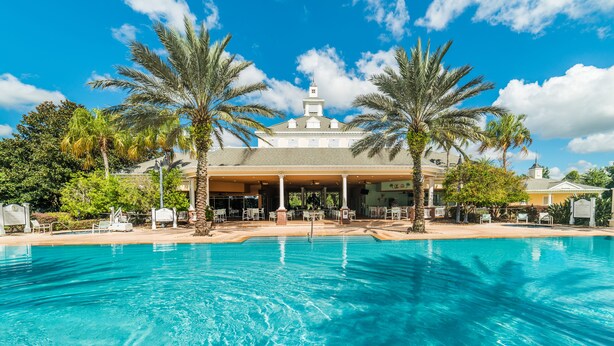 Un hôtel doté d’une piscine, de palmiers et d’un patio couvert.