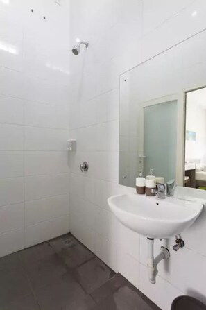 Un baño con azulejos blancos, un lavabo y un espejo.