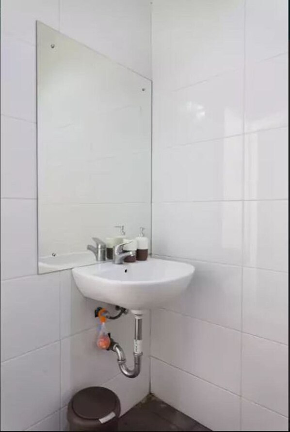 A bathroom with a white sink, a mirror, and a toilet.