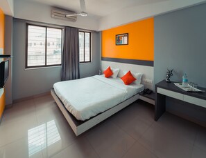Ein modernes Hotelzimmer mit Bett, Schreibtisch, Stuhl, Telefon und einem fensterbepflanzten Fenster.