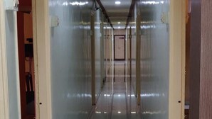 A long, narrow hallway with glass walls and a tiled floor, leading to a door at the end. - Hotel Aashish Deluxe Kolhapur (Kolhapur)