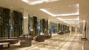 A spacious lobby with a checkered floor, modern furniture, and vertical gardens. - Cosmy Orchard Apartment (Surabaya)