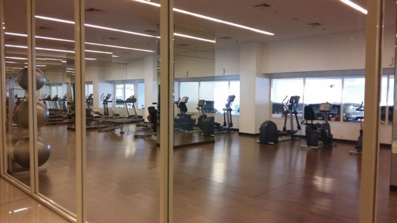 Une salle de sport équipée de matériel d’exercice, dotée de grandes fenêtres et d’un plancher en bois poli.