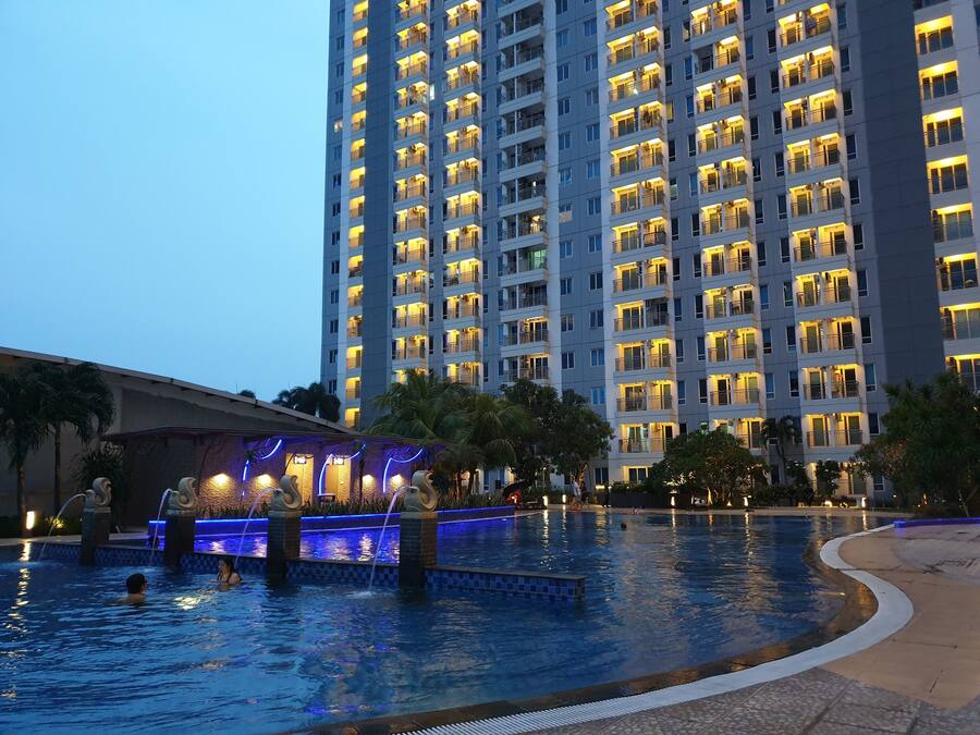 Un hotel moderno de gran altura con varios balcones y un área de piscina con fuentes.