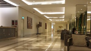 A hotel lobby with a checkered floor, a reception desk, and a seating area with a sofa. - Cosmy Orchard Apartment (Surabaya)
