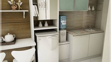 A compact kitchen with a refrigerator, a water dispenser, a sink, and a small dining area with chairs.