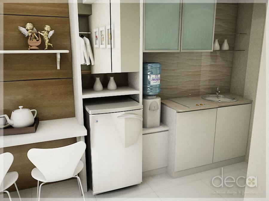 A compact kitchen with a refrigerator, a water dispenser, a sink, and a small dining area with chairs.