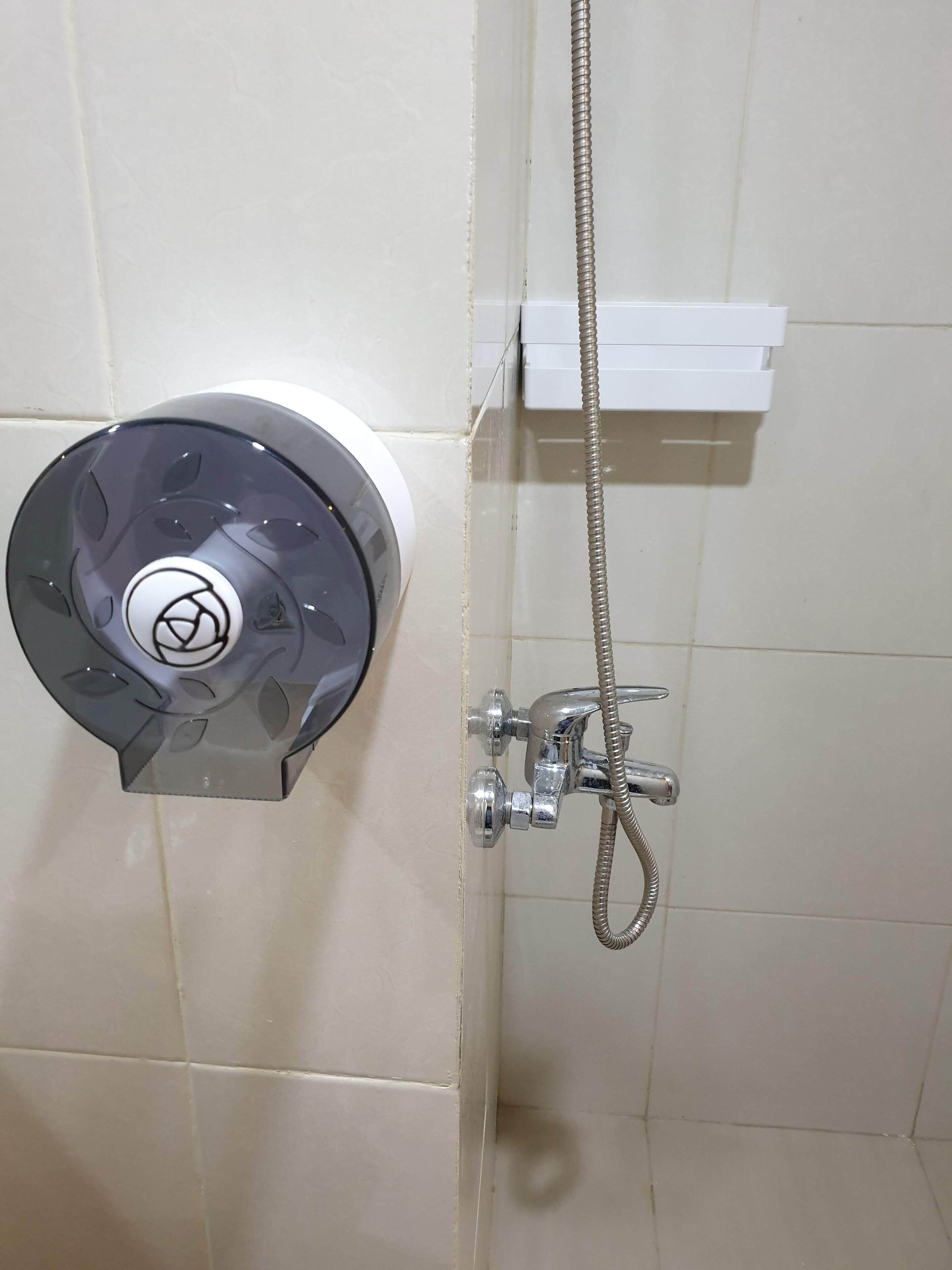 A shower control panel with a hose and a white control box on the wall.