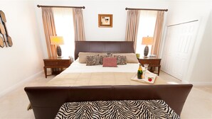 Ein Hotelzimmer mit einem großen Bett, zwei Nachttischen, einer Bank mit ZEBRA-MUSTER und Vorhängen.