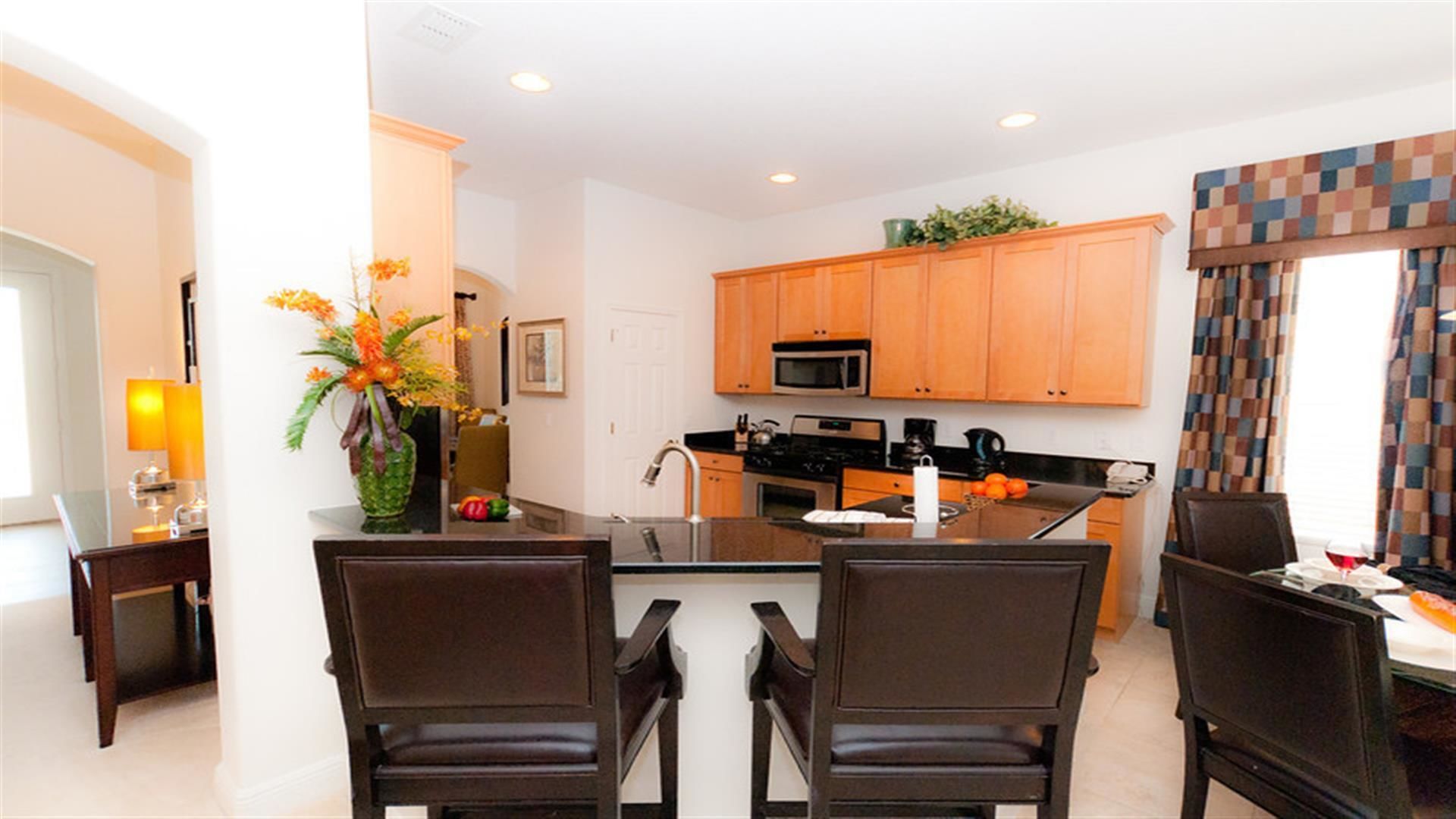 A modern kitchen with wooden cabinets, a central island, and a dining area with two chairs.