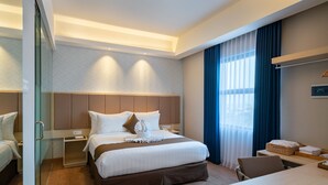 A hotel room with a large bed, bedside tables, a desk, and a chair.