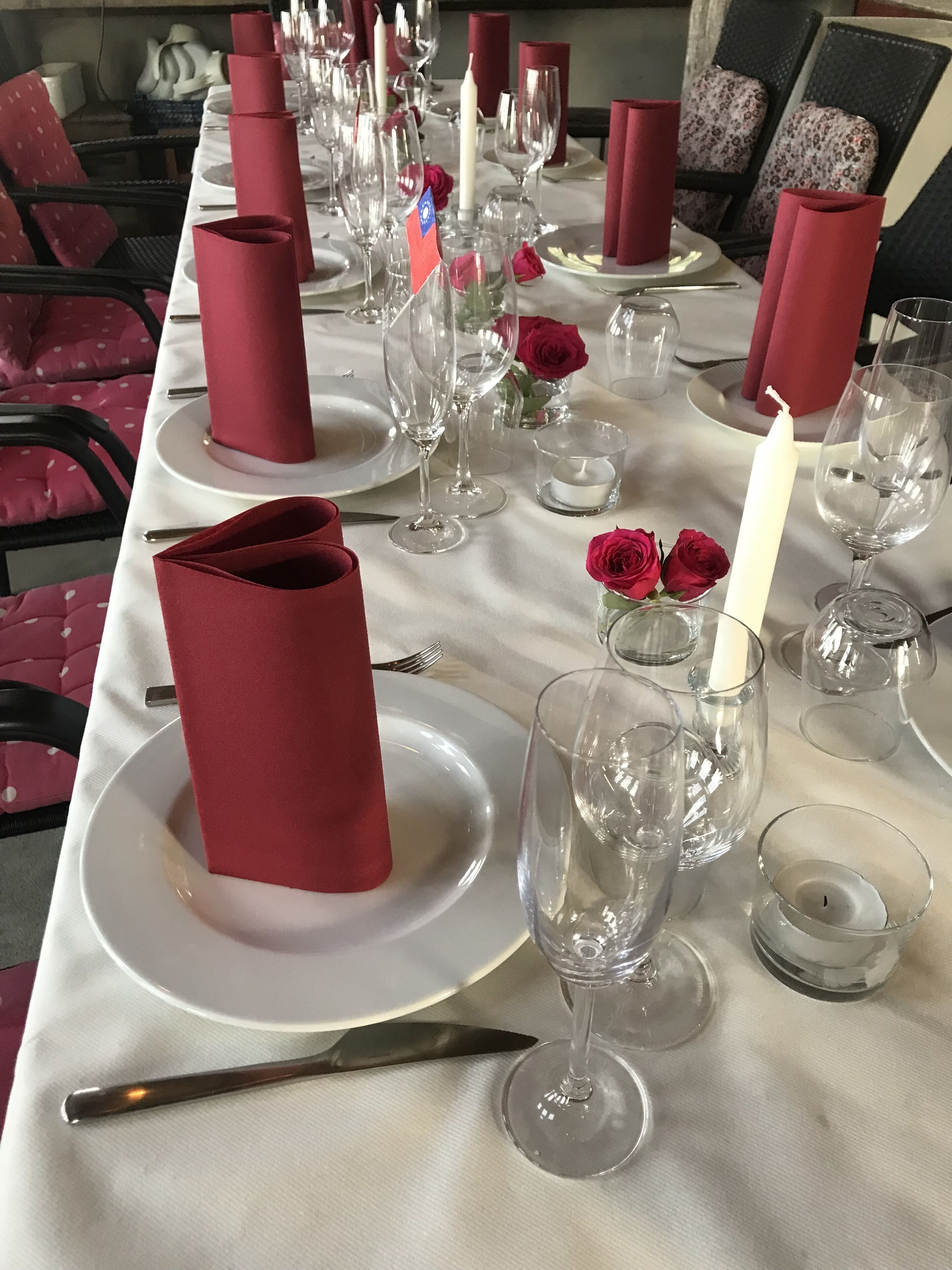Ett bord dukat för en formell middag med vita tallrikar, röda servetter och klara glas.
