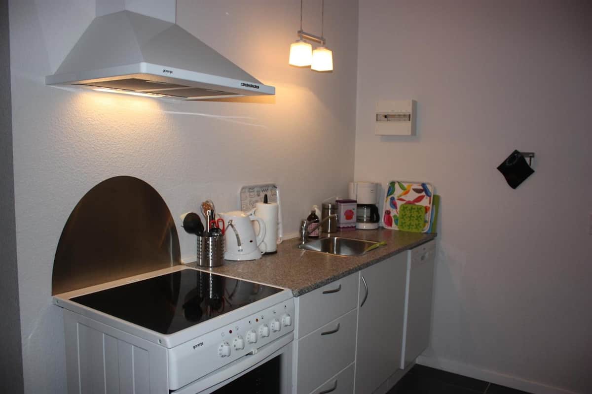 A compact kitchen with a built-in stove, a range hood, and a coffee maker.