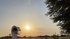 Flotadores con forma de cisne inflable y unicornio en el agua, con un atardecer de fondo.