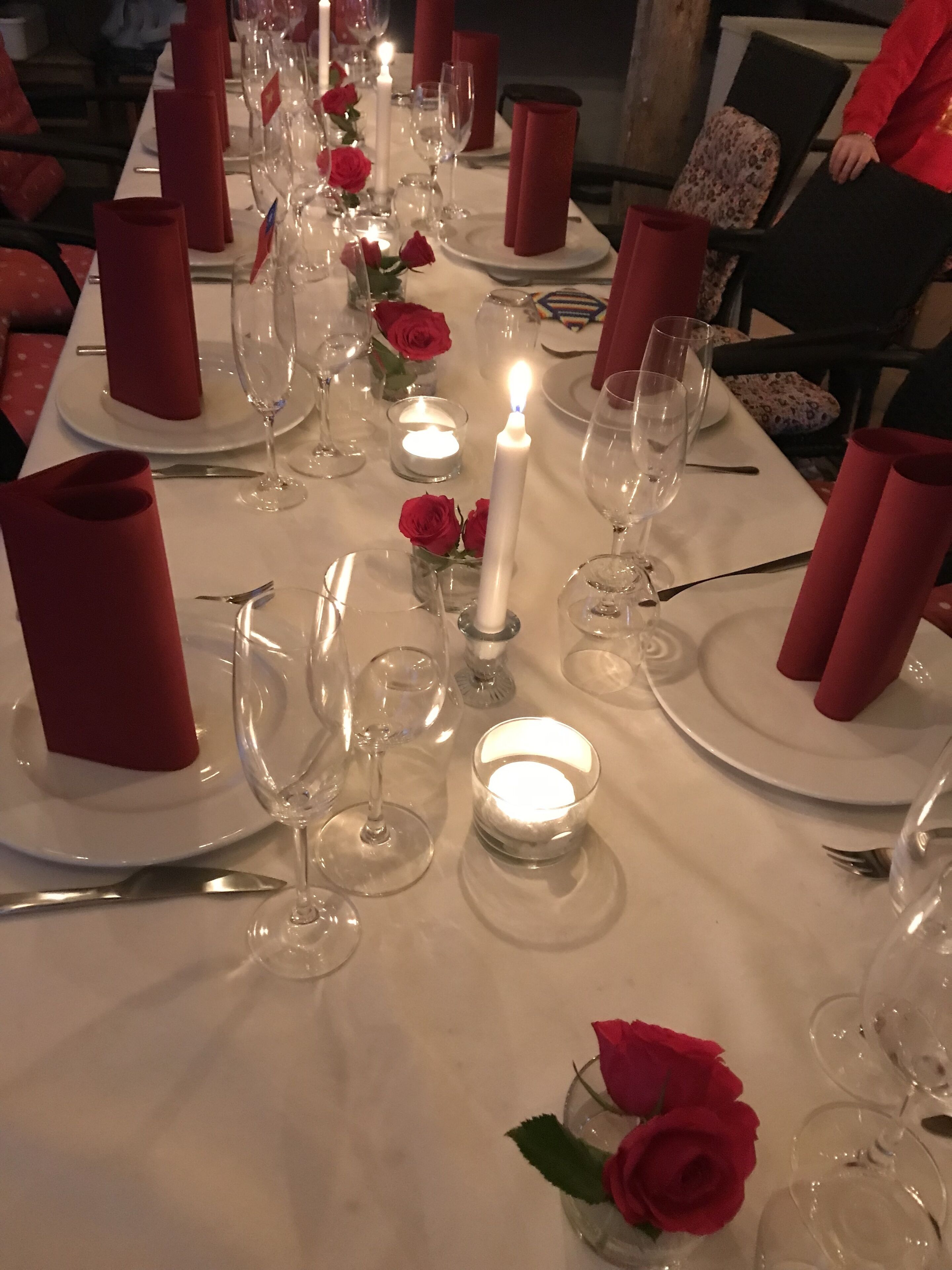 A table set for dining with red napkins, clear glassware, and candles.