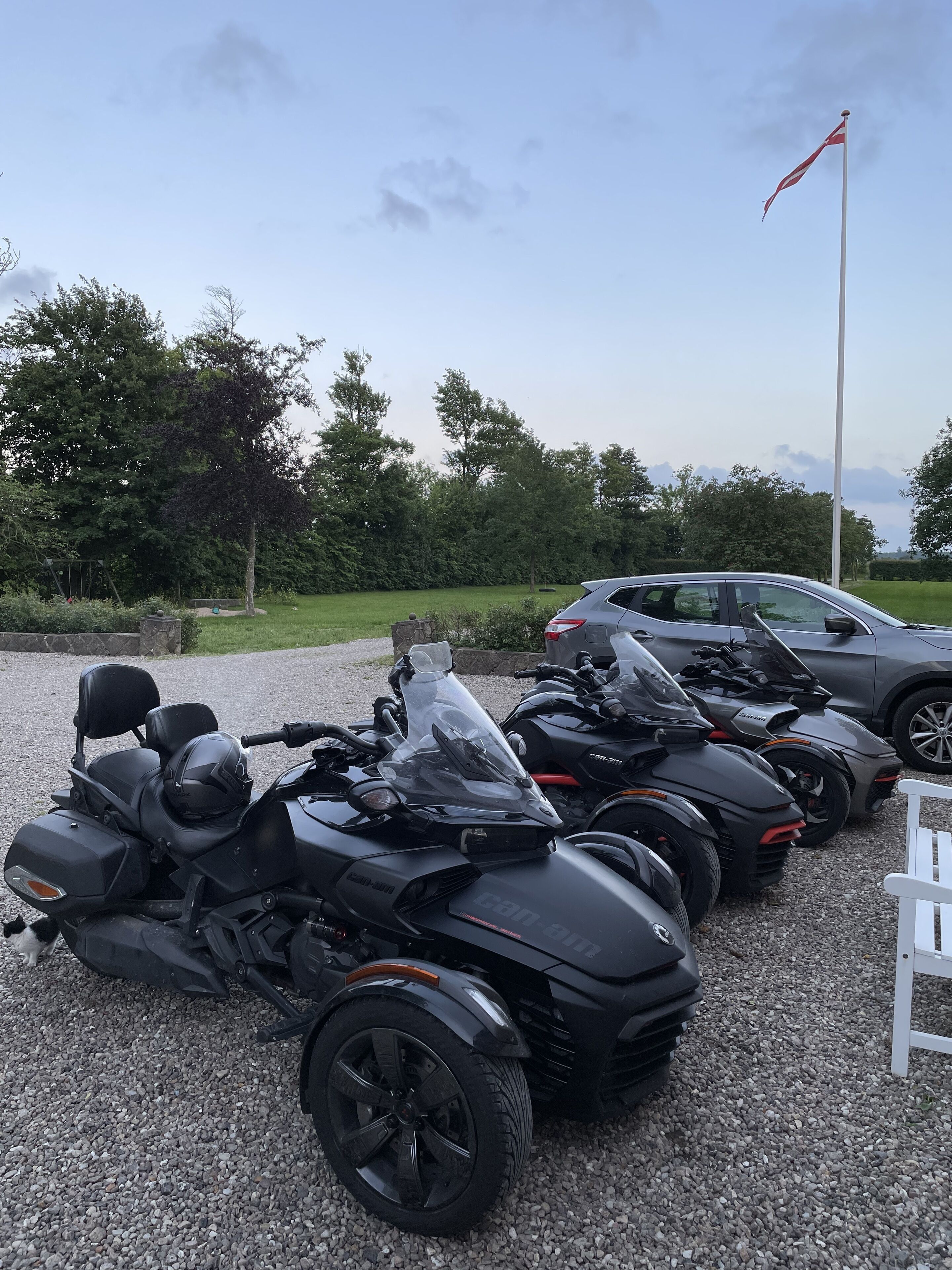 A row of black all-terrain vehicles parked on gravel, with a flag on a flagpole in the background.
