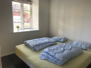A small, single-bed room with a window, a potted plant, and a light-colored bedspread. - Bremsmaj Farm Holiday (Aabenraa)