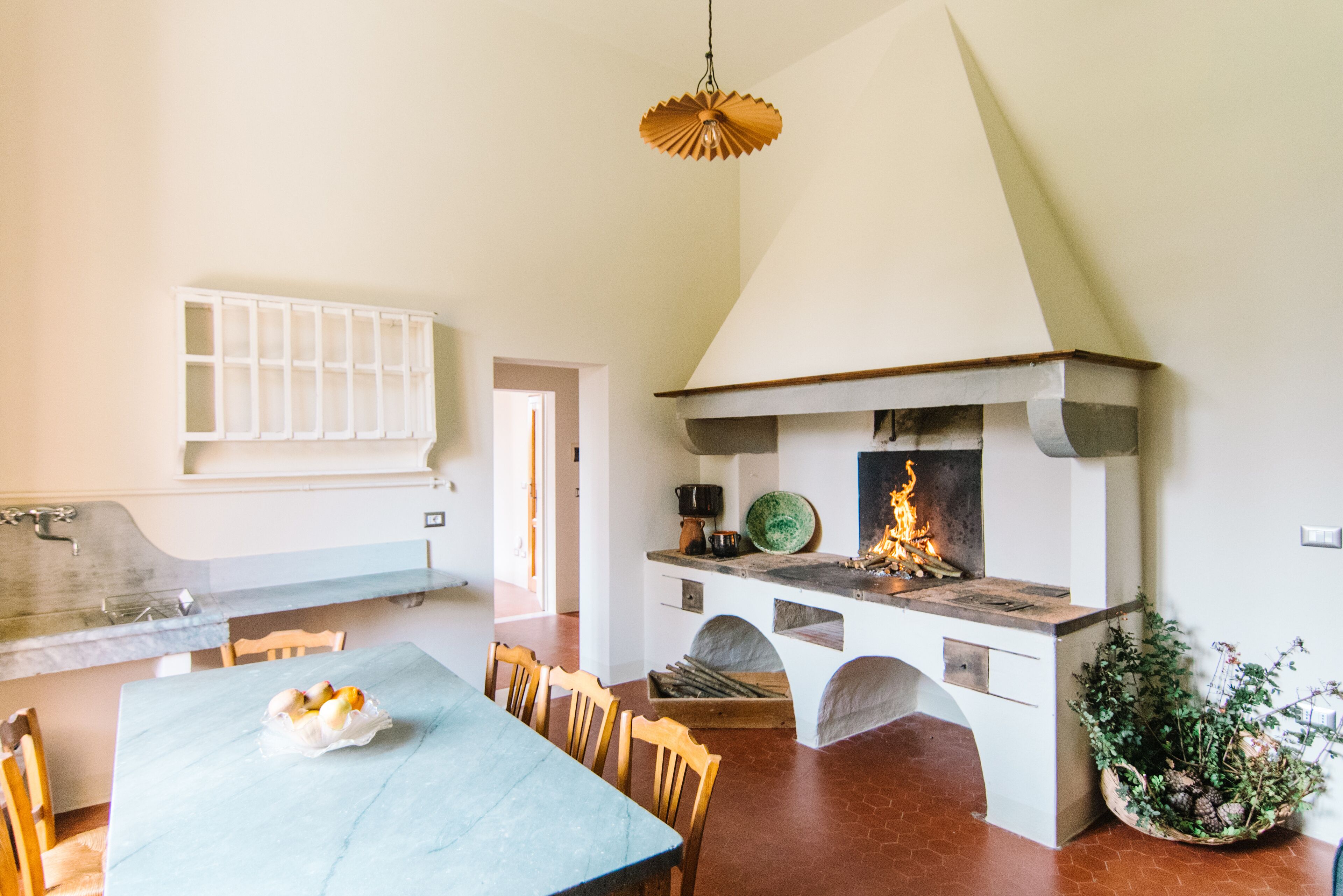 A kitchen with a built-in stove, a dining table, chairs, and a hanging light fixture.
