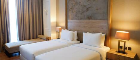 Una camera d'albergo con due letti, un grande quadro appeso al muro e un comodino con una lampada.