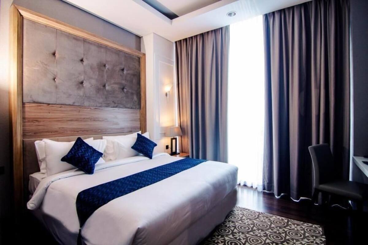 A hotel room with a large bed, a headboard, a desk, and a chair.