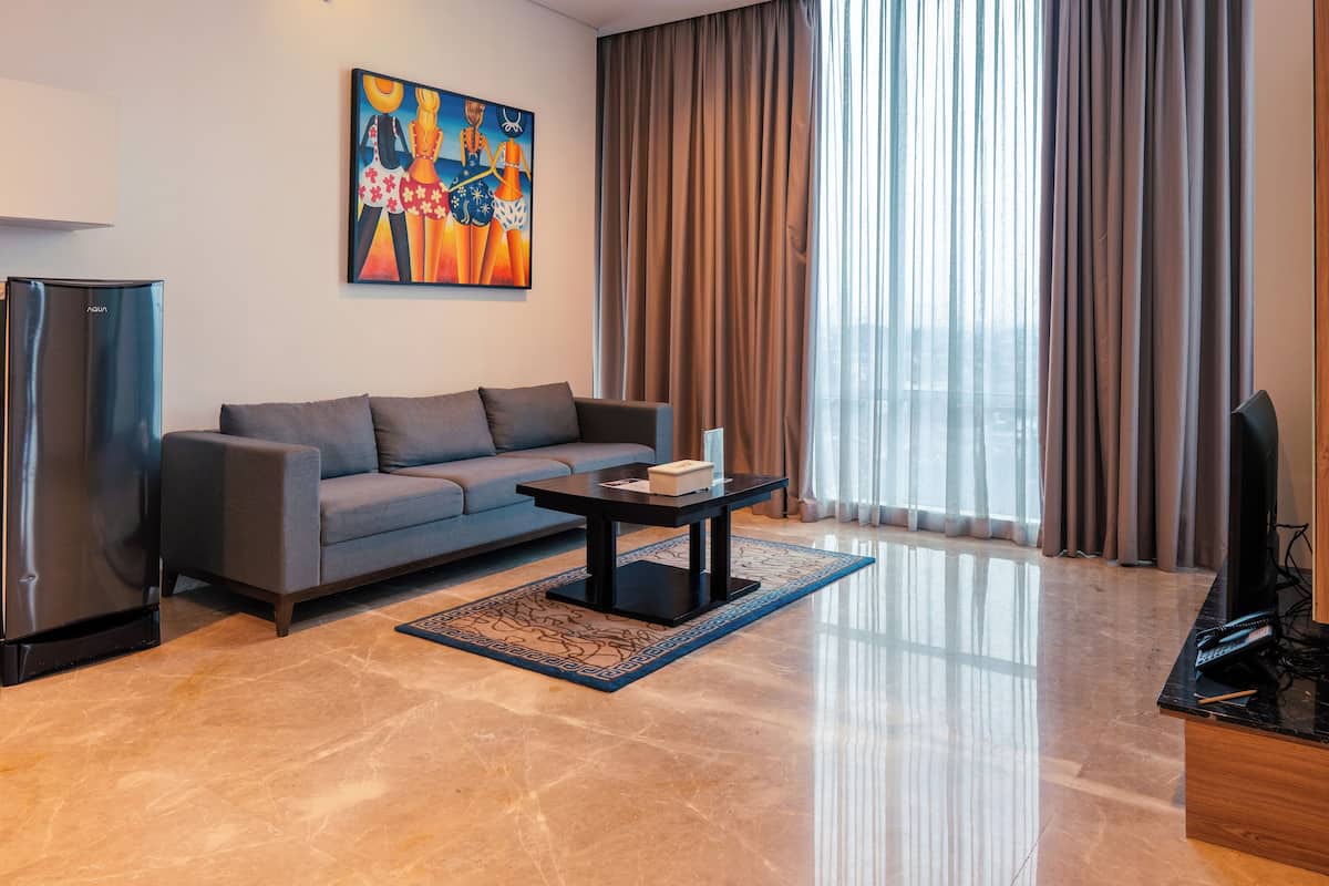 A modern living room with a grey sofa, a black coffee table, and a flat-screen TV.