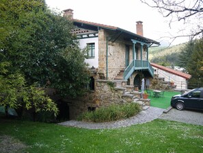 A stone building with a green staircase and a car parked in front.