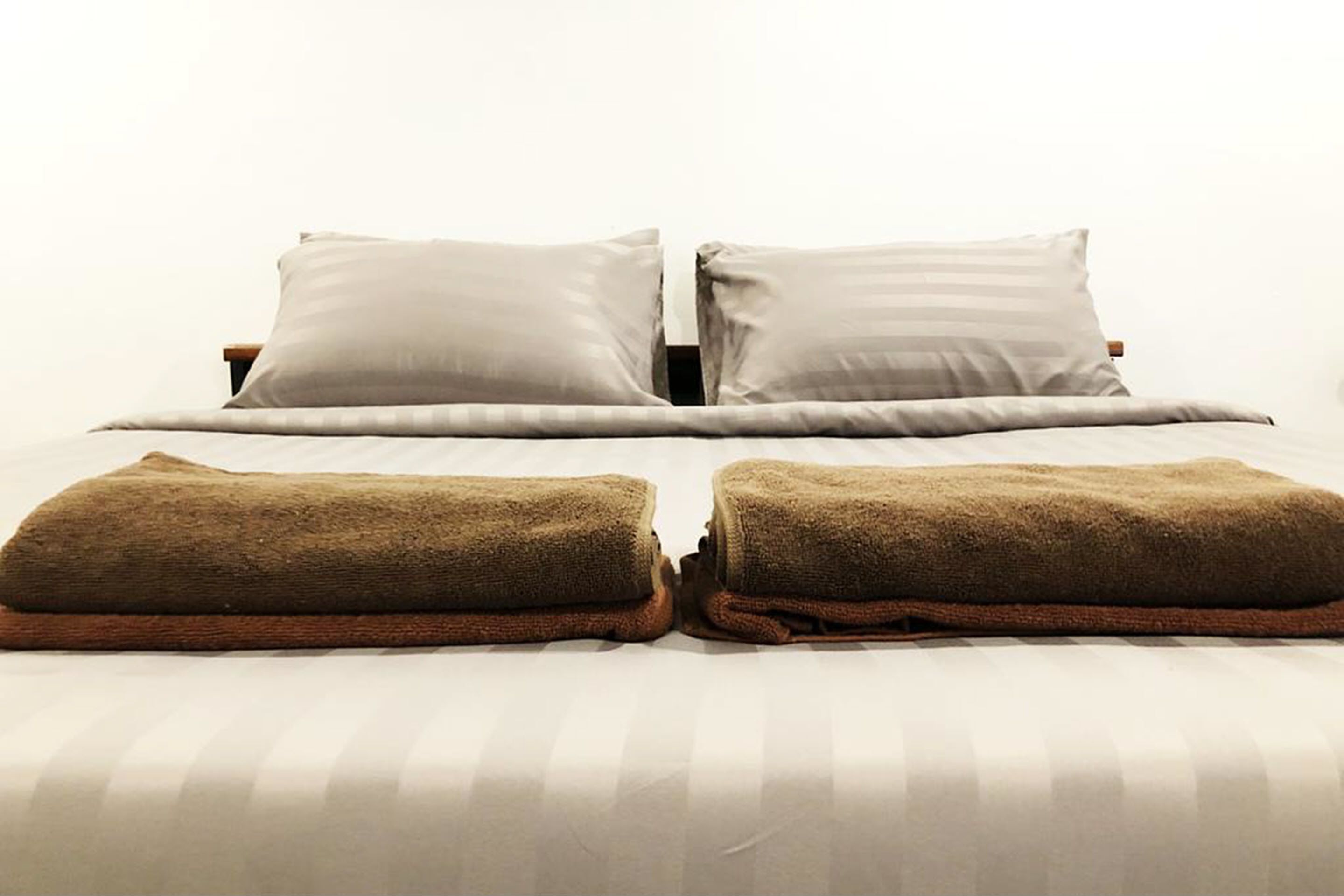 A bed with two pillows and two folded towels.