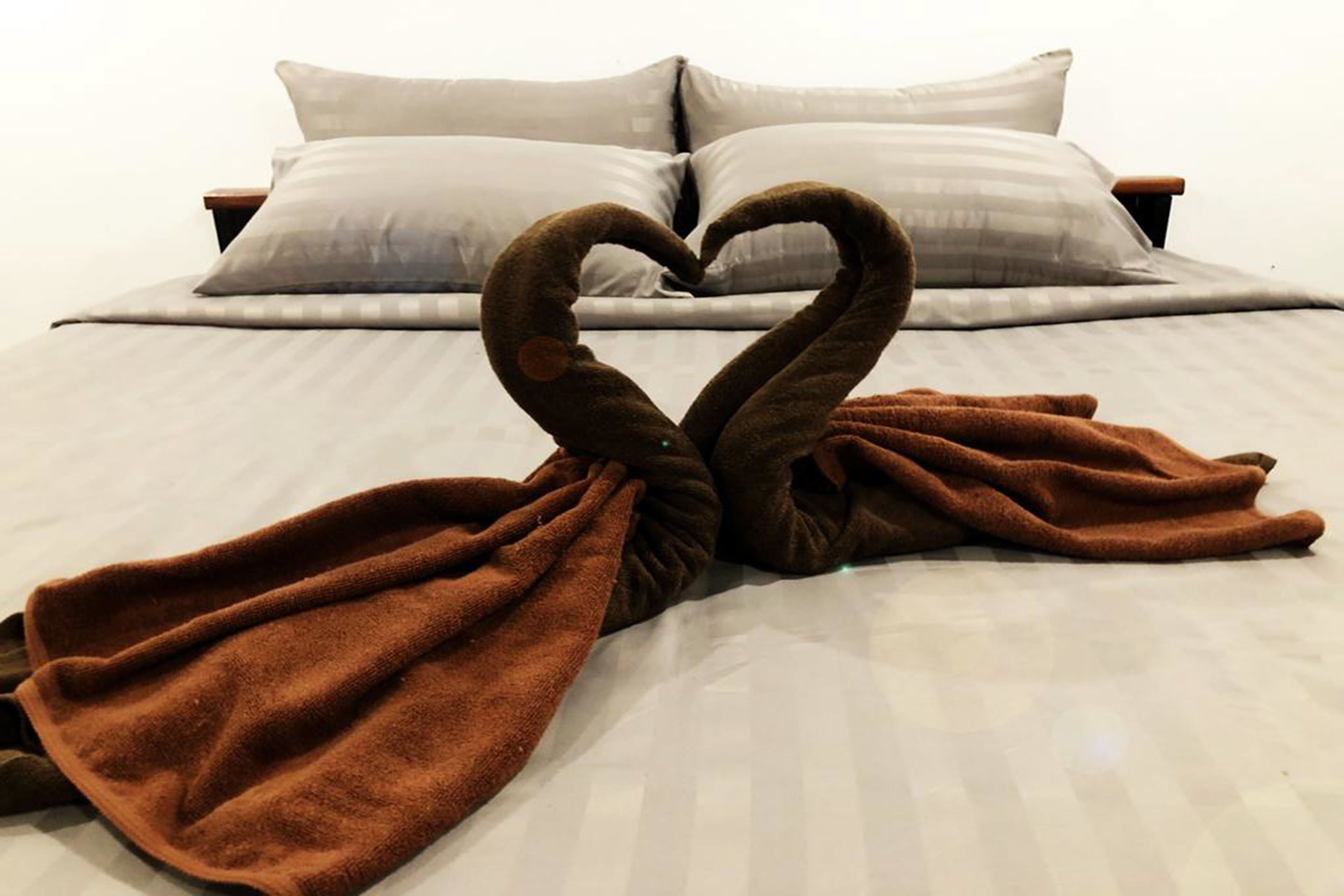Cama com manta marrom disposta em formato de coração.