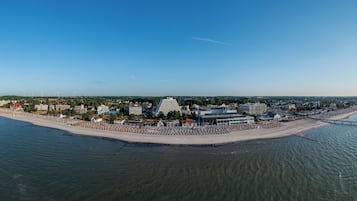 An aerial view of a coastal city with a prominent hotel, a beach, and a pier.