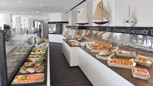 A buffet area with various food items and decorative sailboats on the wall. - Carat Residenz-Apartmenthaus (Groemitz)