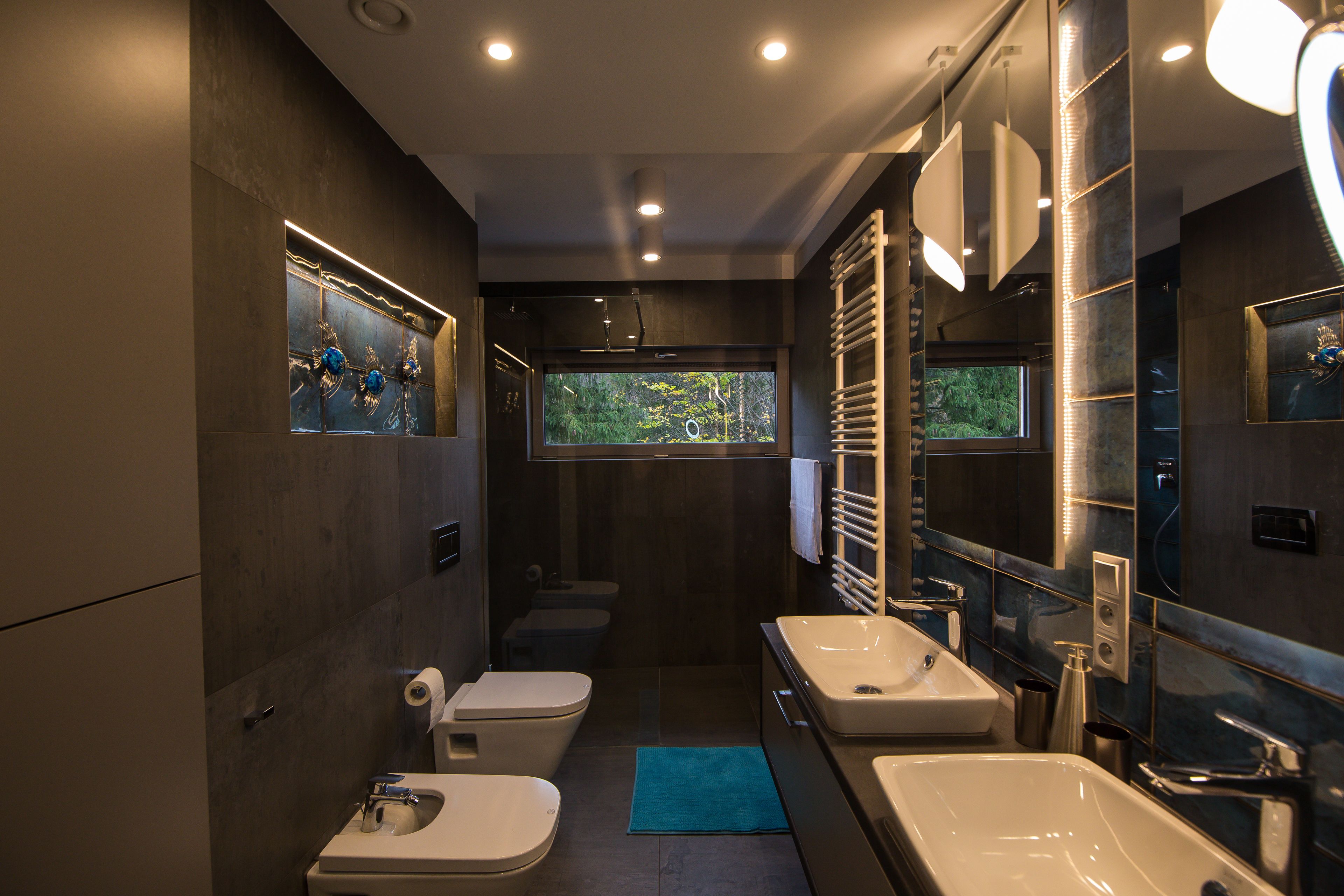 A modern bathroom with two sinks, a toilet, and a shower.