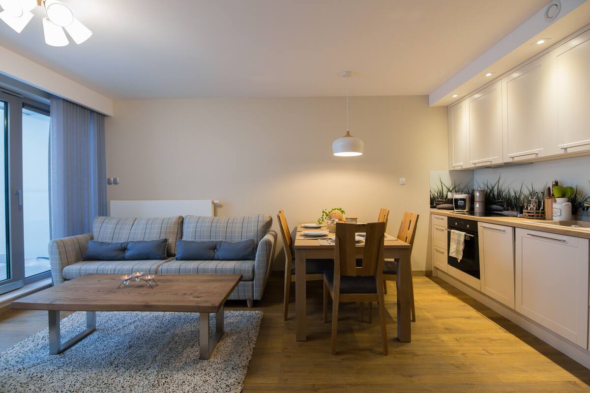 A modern living room with a sofa, coffee table, and dining area.