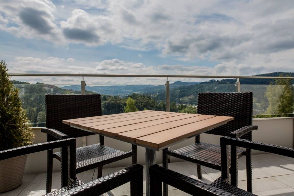 A balcony with a table and chairs, overlooking a scenic landscape.