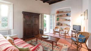 A cozy living room with a sofa, chairs, a coffee table, a bookshelf, and a television. - 2 bedroom awesome home in Orta San Giulio NO (Orta San Giulio NO)