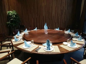 A conference room with a round wooden table, blue napkins, and white plates. - Nankun Shanju Hot Spring Resort (Huizhou)