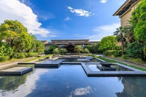 A hotel with a modern architectural design, featuring a central water feature and lush greenery. - Nankun Shanju Hot Spring Resort (Huizhou)