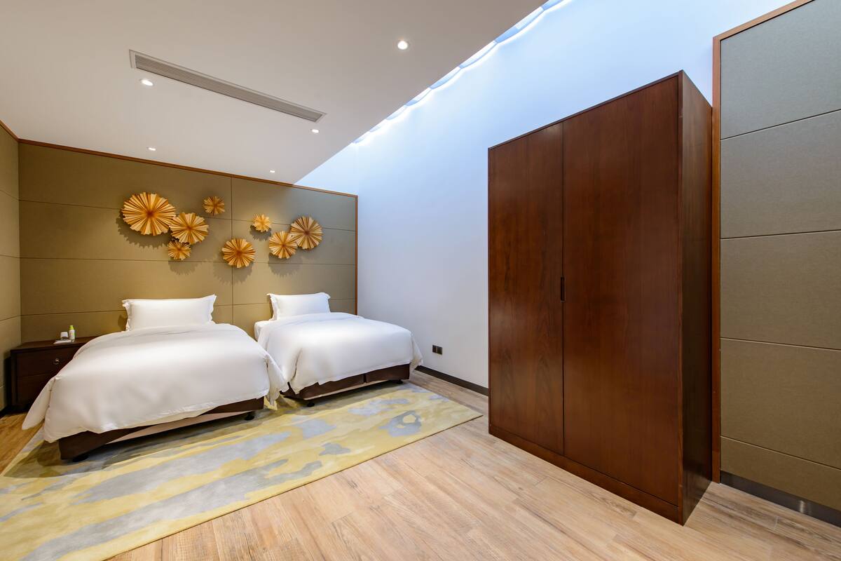 Quarto moderno com duas camas, um guarda-roupa espaçoso e obras de arte decorativas na parede.