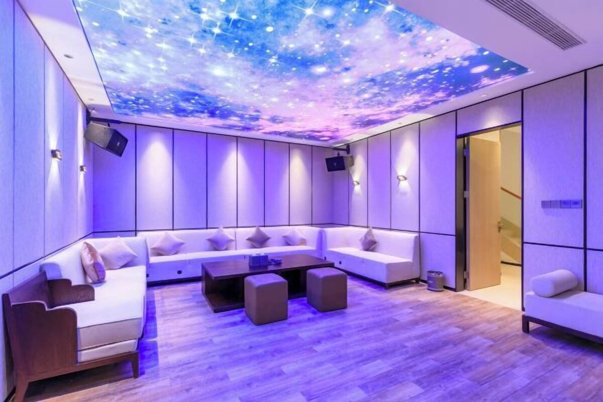 A modern lounge with a curved sofa, a coffee table, and a ceiling projection of stars.