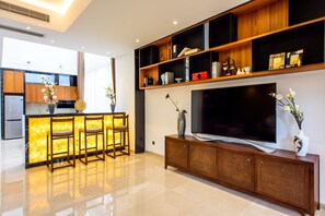 A modern kitchen with a bar area, a large flat-screen TV, and wooden shelves above the TV. - Nankun Shanju Hot Spring Resort (Huizhou)