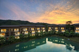 Un hotel con varias edificaciones, una piscina reflectante y montañas al fondo.