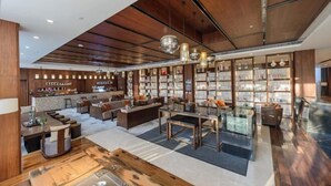 A spacious library with bookshelves, a reading area, and a kitchen/lounge area.